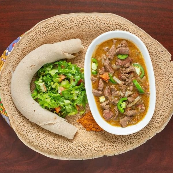 Elsi Ethiopian Restaurant's Kitfo, a dish of injera bread, beef stew, and a side salad.