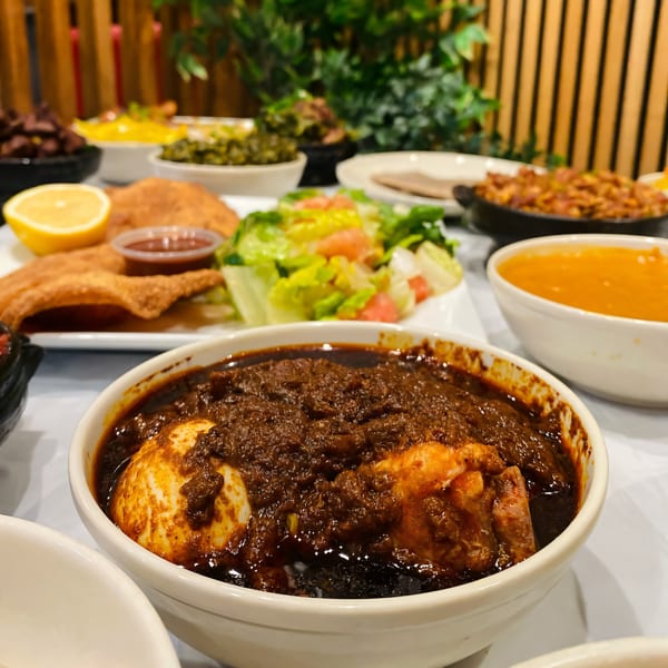 Close-up of a bowl of Ethiopian Doro Wat with eggs, surrounded by other dishes.